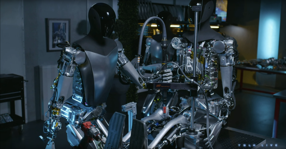 Screenshot of 2 humanoid robots building a third one, from Tesla 2023 Investor Day